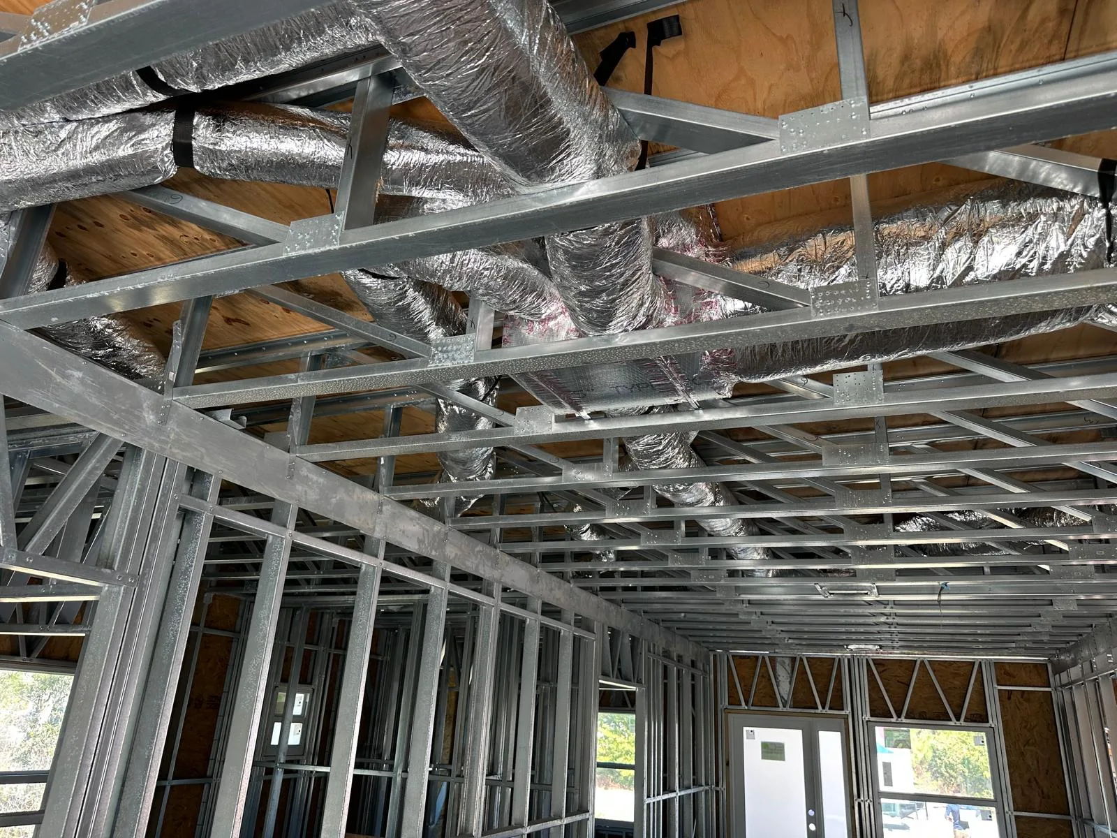 New construction HVAC ductwork installed above residential metal framing